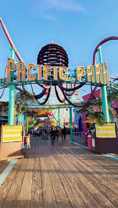 the entrance to an amusement park with people walking around