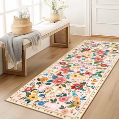 a white rug with colorful flowers on it in front of a bench and vases