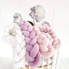 a bunch of pillows sitting on top of a wooden table next to a white flower