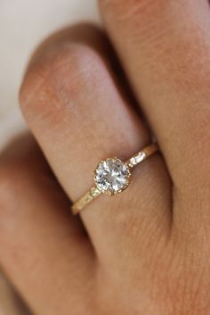 a woman's hand with a diamond ring on top of her finger, showing the center stone