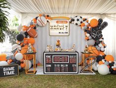 an orange and black sports themed party with balloons, football signs, soccer balls, and game time decorations