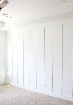 an empty room with white paint and wood paneling on the walls is pictured in this image