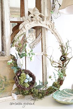 an old mirror is decorated with greenery and eggs in a wreath on the mantle