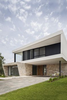 the modern house is located in an open area with grass and flowers on the lawn