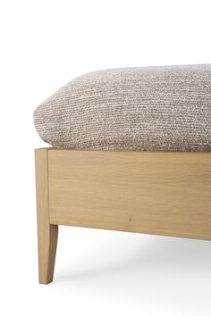 an upholstered footstool with a wooden frame and fabric seat cushion on it