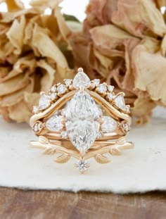 a close up of a wedding ring on a table with flowers in the back ground