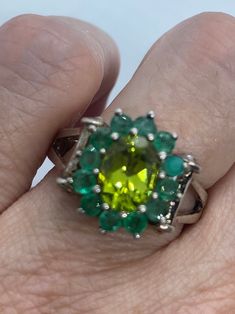 Rich and very bright green peridot ring surrounded by Emerald  Sterling silver  Size 8 can be sized by my jeweler. His service charge is $20  All rings are shipped in a nice gift box.   Check out our over a THOUSAND great reviews Engraving is $4 per letter and is not always perfect depending on the piece. It can take a few days if the jeweler is busy. This is payable to Paypal Judithsltd@gmail.com  PLEASE NOTE If we have multiples of the same vintage item, it is because we often purchase factory Green Multi-stone Emerald Rings, Lime Green Sterling Silver Rings As Gift, Lime Green Sterling Silver Rings For Gift, Green Emerald Ring With Accent Stones For May Birthstone, Green Multi-stone Emerald Ring For May Birthstone, Green Emerald Cluster Ring With Multi-stones, Emerald Cut Peridot Ring In Green, Green Emerald Cut Peridot Ring, Formal Green Birthstone Ring With Halo Setting