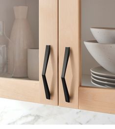 black handles on wooden cabinet doors with plates and bowls in the backgrouf