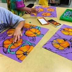 two children are doing arts and crafts on purple paper with orange flowers in the middle