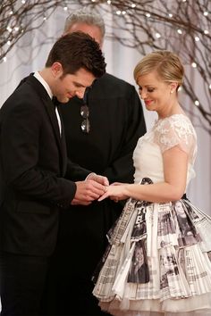 a man and woman standing next to each other in front of a tree with lights