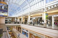 the inside of a shopping mall with people walking and riding on escalators in it