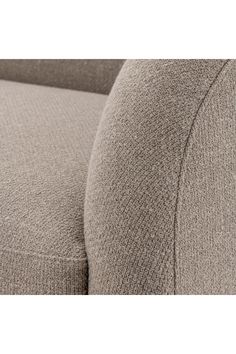 a close up view of the arm and back of a couch with a light brown fabric