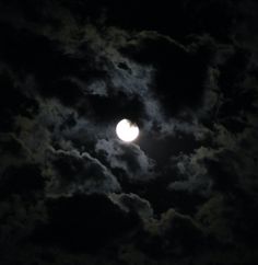 the moon is shining brightly in the dark sky with clouds around it and on its side