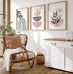 three framed art prints hang on the wall next to a chair and sideboard in a white room