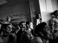 a group of people sitting in a living room watching something on the wall and laughing