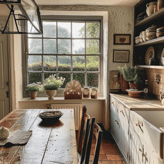 a kitchen with a wooden table surrounded by pots and pans on the windowsill