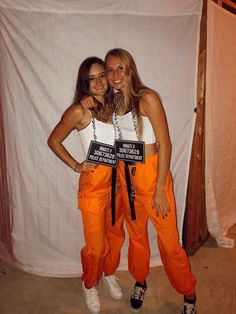 two women standing next to each other wearing orange pants