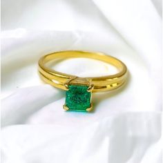 a close up of a ring with a green stone in it on a white cloth