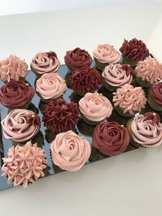 cupcakes decorated with pink and red frosting on a blue tray in front of a white wall