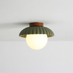 a ceiling light with a green dome on it's side and a white wall in the background