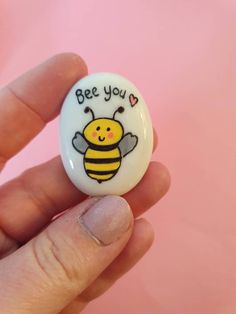 a hand holding a button with a bee on it that says be you and hearts