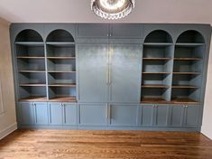 an empty room with blue bookcases and wooden floors