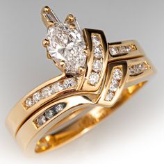 two gold wedding rings with diamonds on each one and an oval shaped diamond in the middle