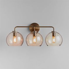 three light bathroom fixture with clear glass globes on the bottom and an antique brass finish