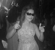 black and white photo of a woman in sunglasses giving the peace sign at a party