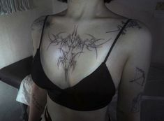 a woman with tattoos on her chest wearing a bra