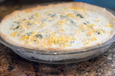 a quiche with cheese and spinach in a glass dish on a granite counter