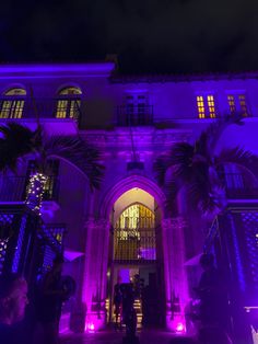 people standing in front of a building with purple lights