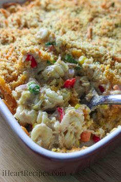 a casserole dish with chicken, pasta and vegetables in it on a wooden table