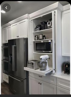 a kitchen with white cabinets and stainless steel appliances in the corner, including an appliance