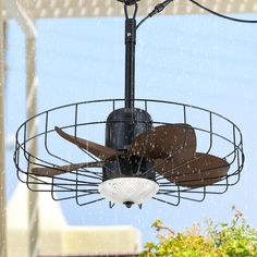 a ceiling fan that is hanging from the ceiling in front of a window with rain falling on it