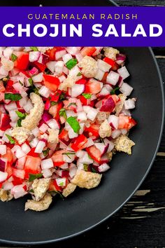 a black plate topped with chopped vegetables on top of a wooden table next to a fork