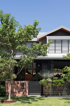 a house that is surrounded by trees and grass in the front yard with an iron fence