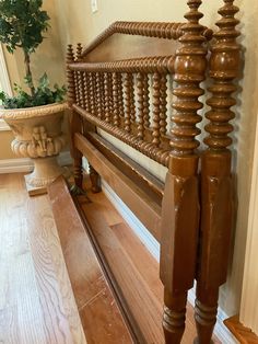 a wooden bed frame with wood slats on the headboard and foot board, next to a potted plant