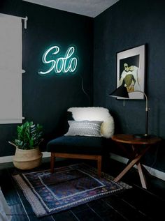 a living room with black walls and a neon sign on the wall above a chair