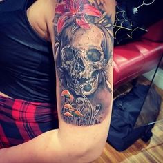 a woman's arm with a skull and flower tattoo on the left side of her arm