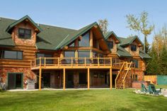 a large wooden house with green roofing and stairs leading up to the upper level