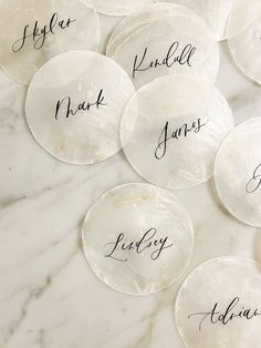 six personalized glass coasters sitting on top of a white marble table with black writing