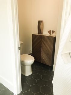 a white toilet sitting in a bathroom next to a wooden cabinet with two vases on top of it