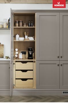 a kitchen with grey cupboards and white walls, coffee maker on the far wall