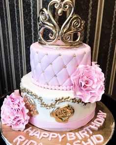 a three tiered cake with pink flowers and a tiara on top that says happy birthday