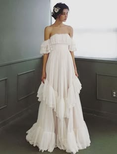 a woman standing in front of a window wearing a dress with ruffles on it