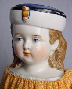 a close up of a child's head wearing a white hat and orange dress