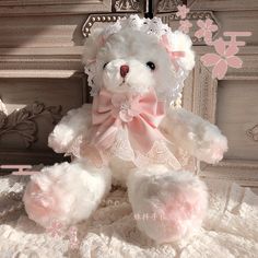 a white teddy bear sitting on top of a bed next to a wall with pink flowers