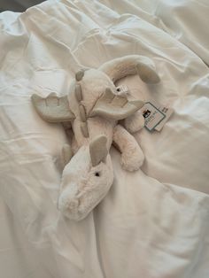 a stuffed animal laying on top of a white bed