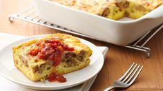 an omelet with meat and tomato sauce on a plate next to a casserole dish